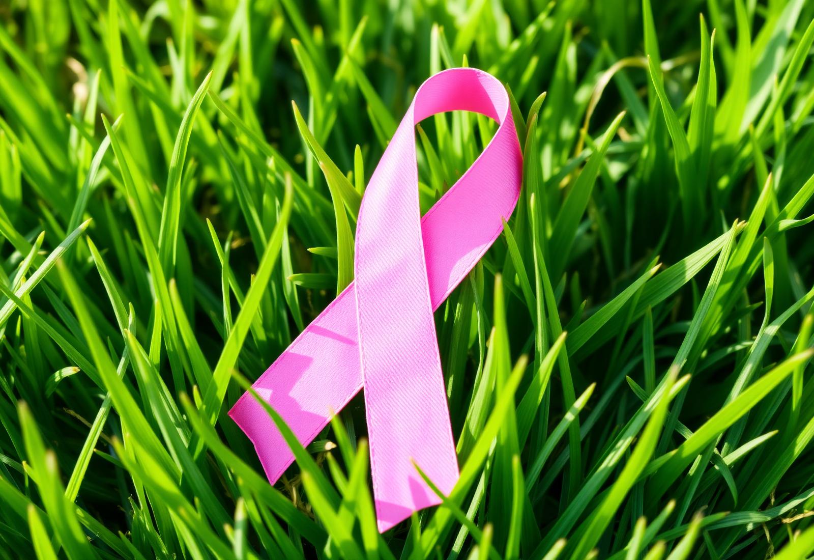 Pink ribbon in the grass symbolizing our support for cancer charities